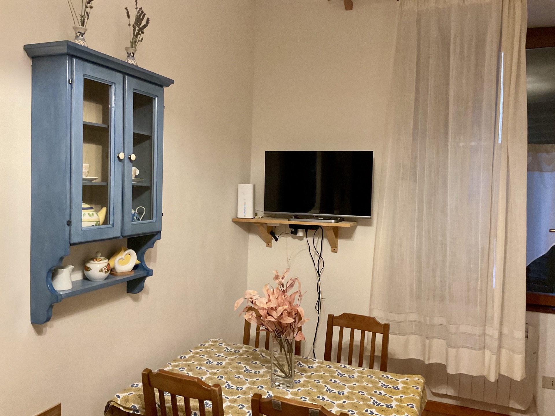 Zona pranzo di Al Duomo con vetrina blu e tavolo in legno